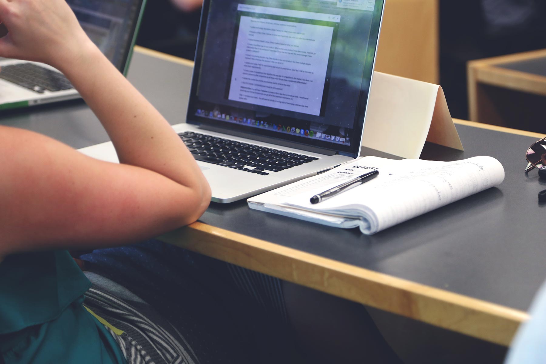 Laptop met een document open naast een notitieblok